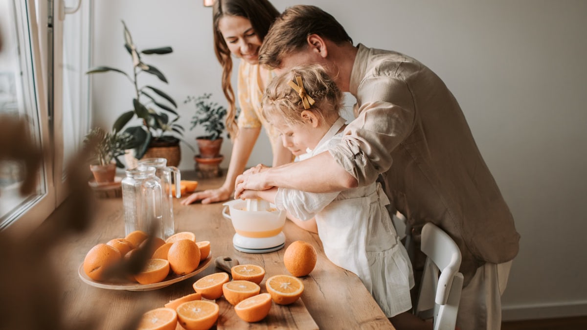 A family enjoys making fresh orange juice together in a warm and inviting kitchen setting.